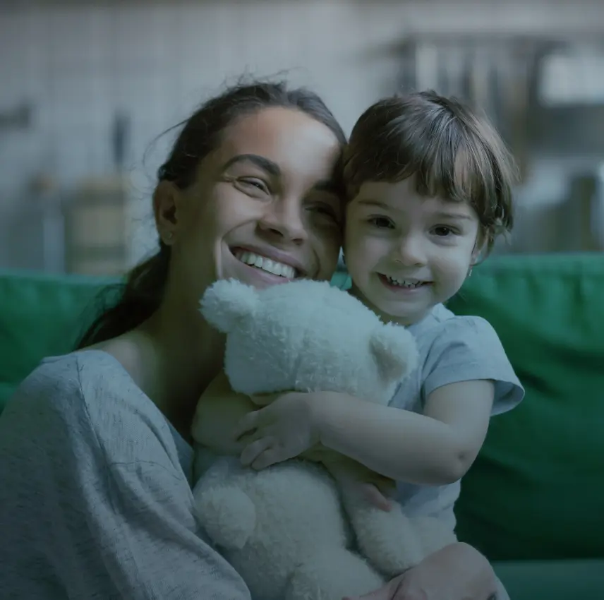 smiling mom hugging daughter with a teddy bear