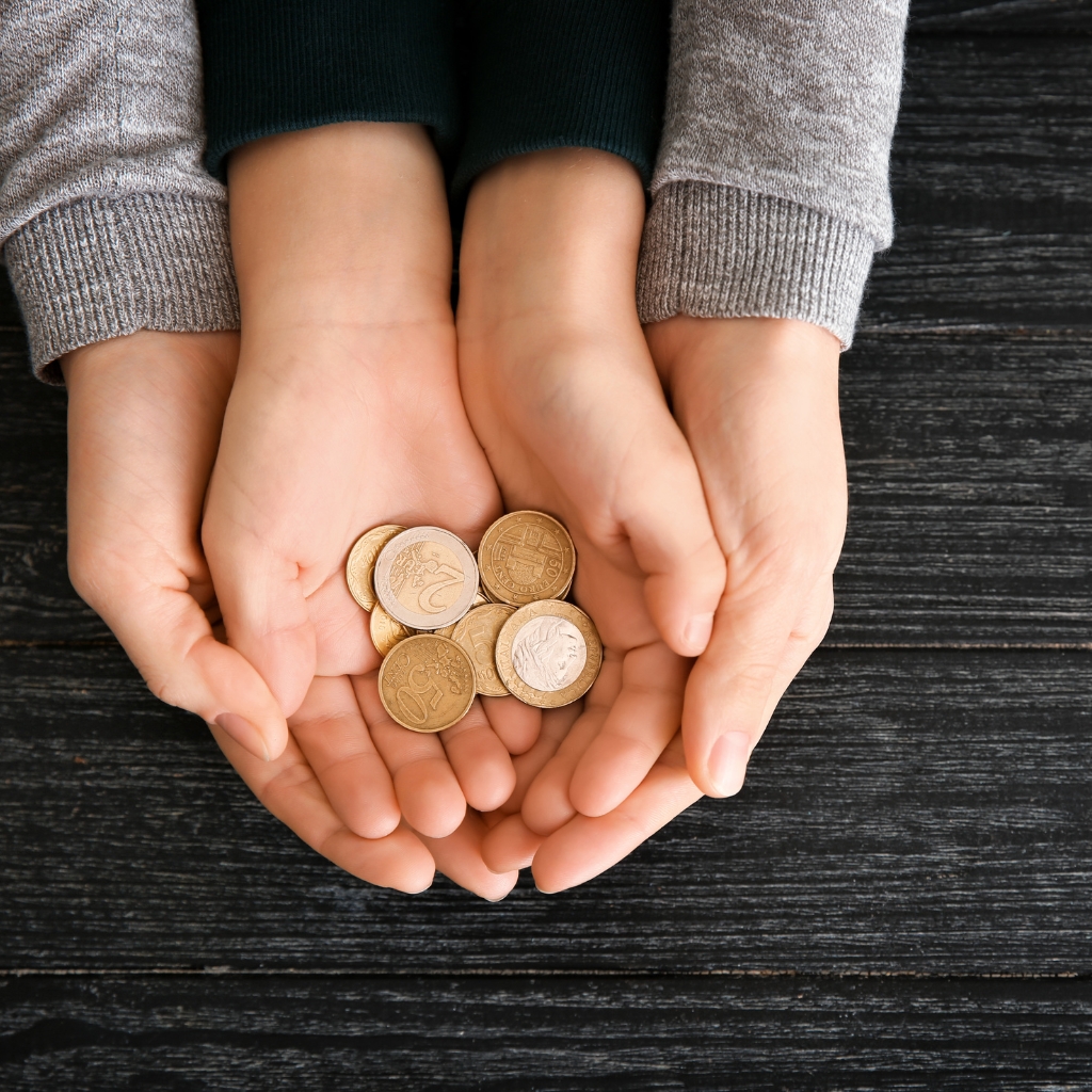 Hands of woman and his son holding coins on wooden table.